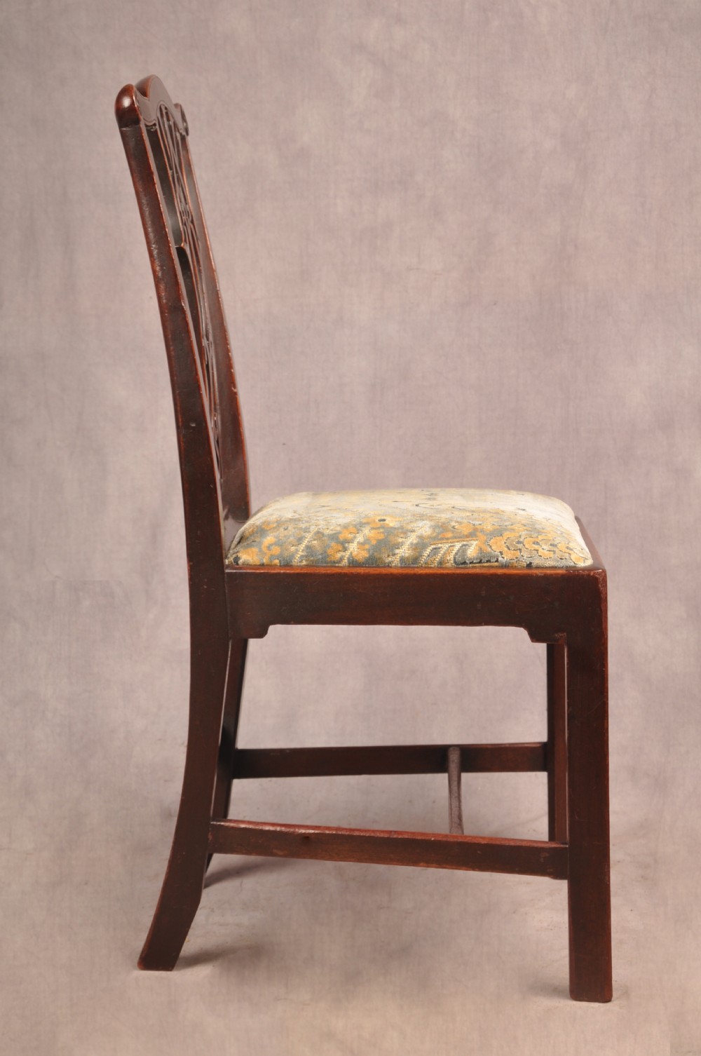 A set of six mahogany Chippendale style dining chairs featuring intricate pierced back splats and patterned upholstered drop-in seats. View VI