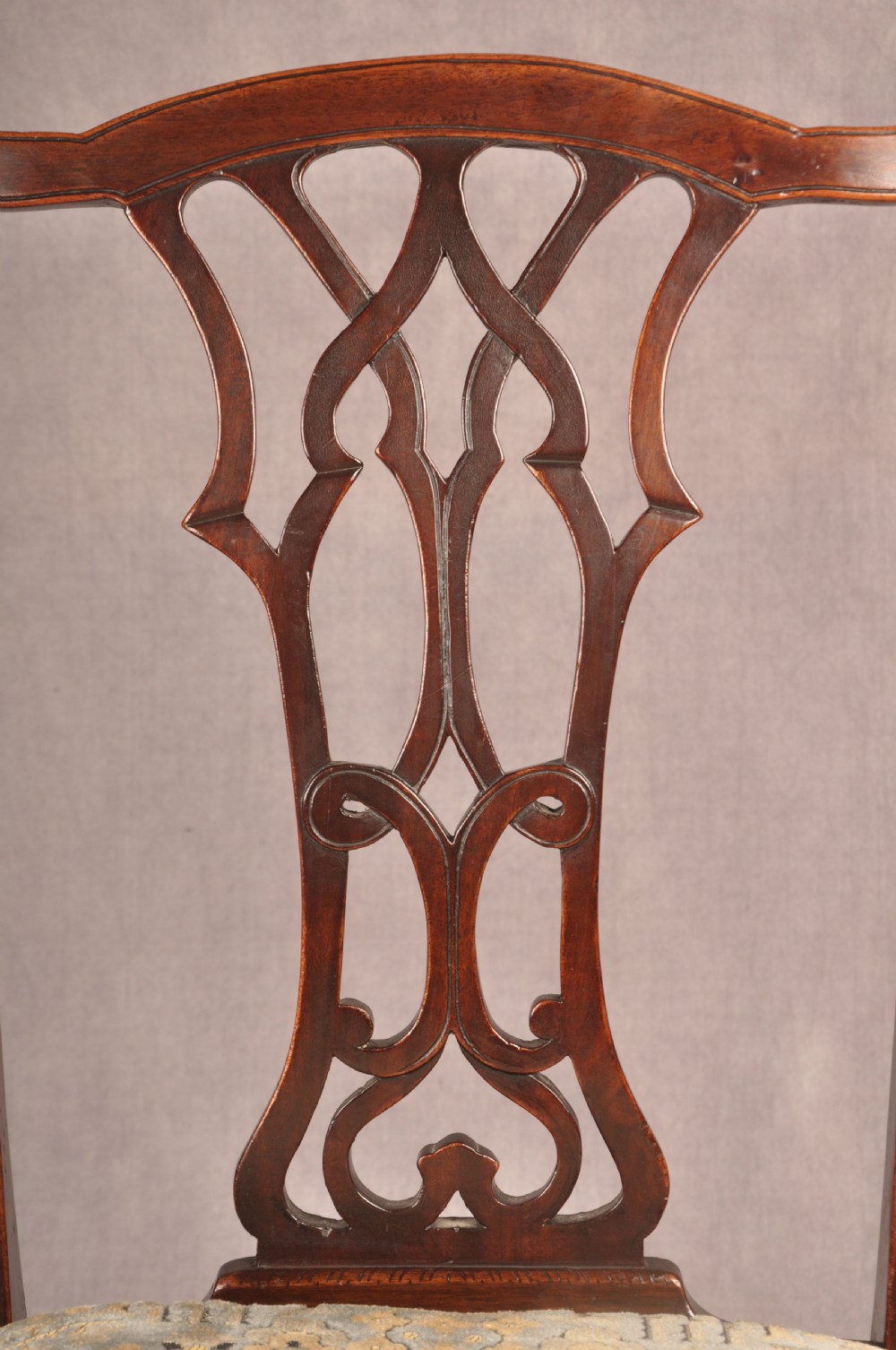 A set of six mahogany Chippendale style dining chairs featuring intricate pierced back splats and patterned upholstered drop-in seats. View IX