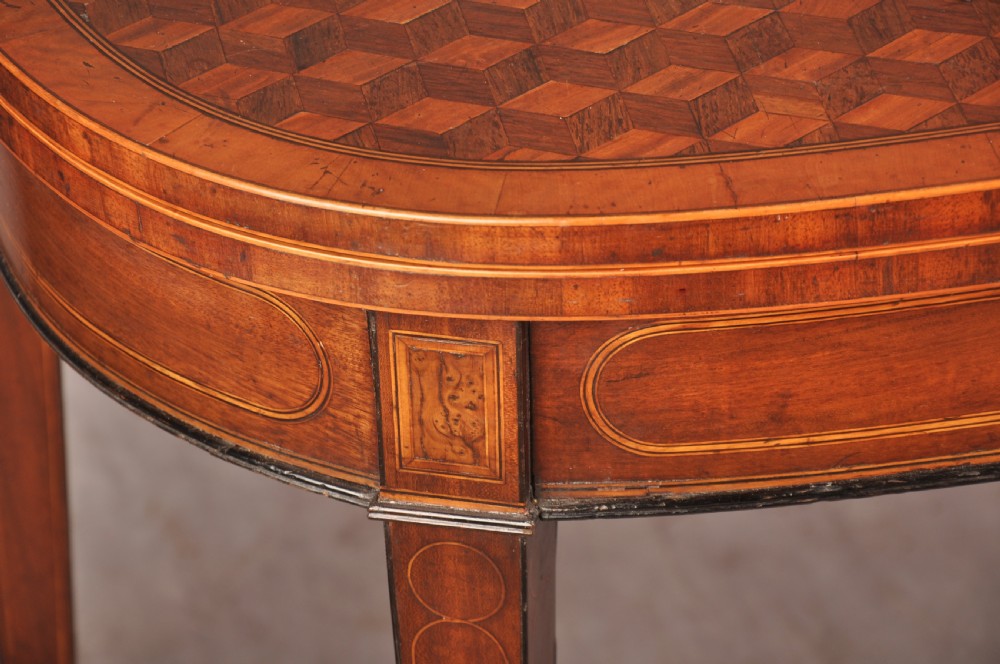 An 18th-century demilune card table featuring a geometric parquetry top, inlaid apron, and four square tapered legs ending in spade feet. View IV