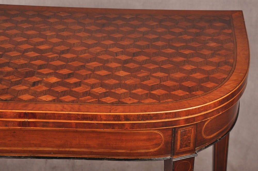An 18th-century demilune card table featuring a geometric parquetry top, inlaid apron, and four square tapered legs ending in spade feet. View VI
