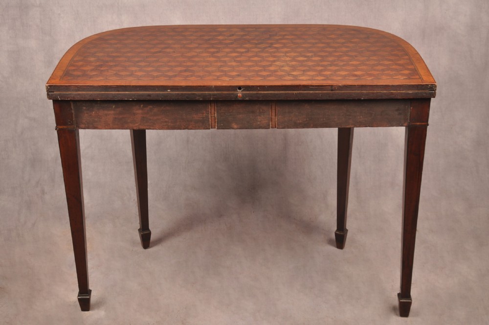 An 18th-century demilune card table featuring a geometric parquetry top, inlaid apron, and four square tapered legs ending in spade feet. View IX