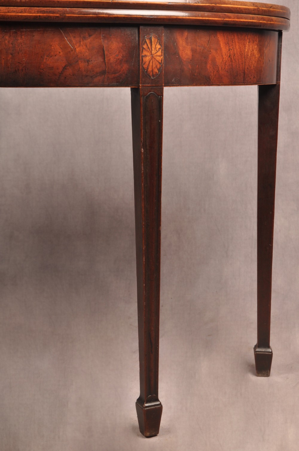 An 18th-century demilune mahogany tea table featuring tapered legs with inlaid patera motifs and spade feet. View IV