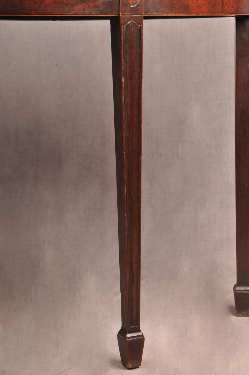 An 18th-century demilune mahogany tea table featuring tapered legs with inlaid patera motifs and spade feet. View V