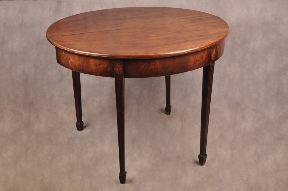 An 18th-century demilune mahogany tea table featuring tapered legs with inlaid patera motifs and spade feet. View VII