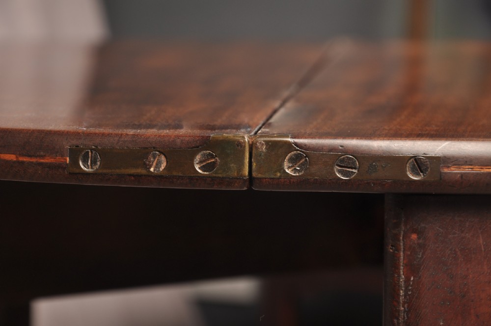 An 18th-century demilune mahogany tea table featuring tapered legs with inlaid patera motifs and spade feet. View X