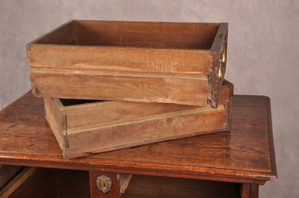 A Charles II dark oak chest of drawers featuring geometric moulded drawer panels, brass teardrop handles, keyhole escutcheons, and bun feet. View XIII