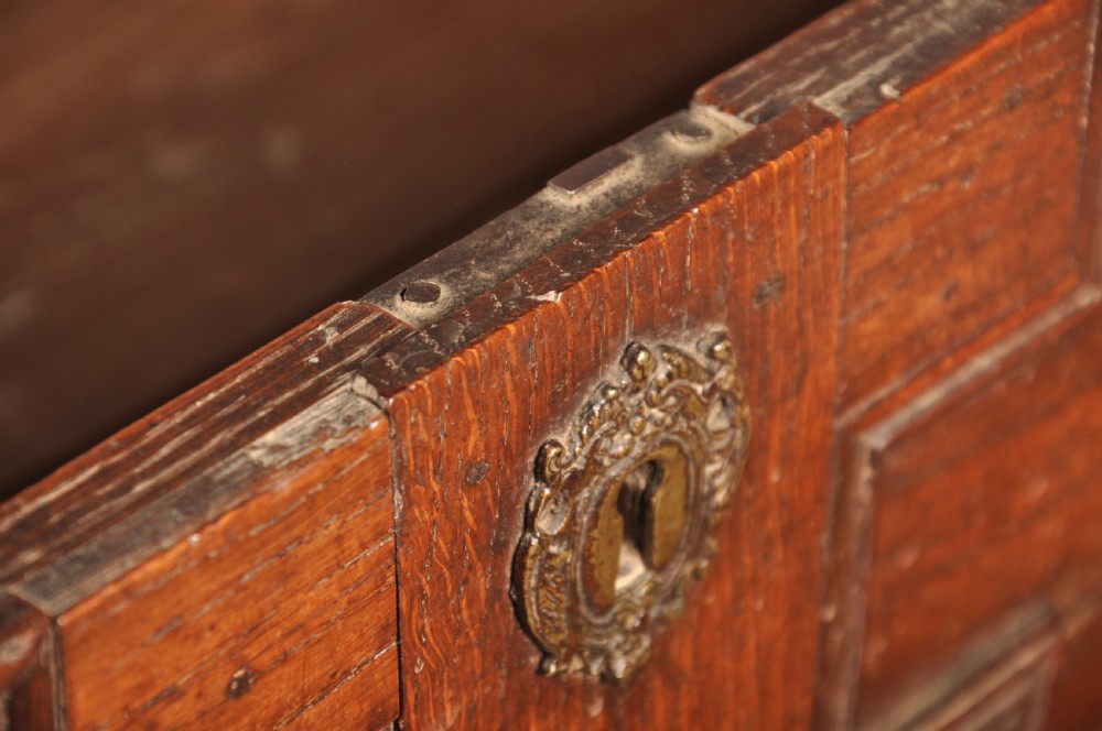 A Charles II dark oak chest of drawers featuring geometric moulded drawer panels, brass teardrop handles, keyhole escutcheons, and bun feet. View XV