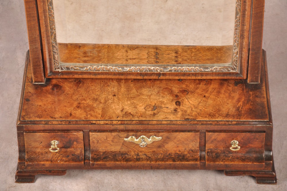 An 18th-century walnut toilet mirror featuring a rectangular adjustable glass frame resting above a three-drawer box base with brass handles. View IV