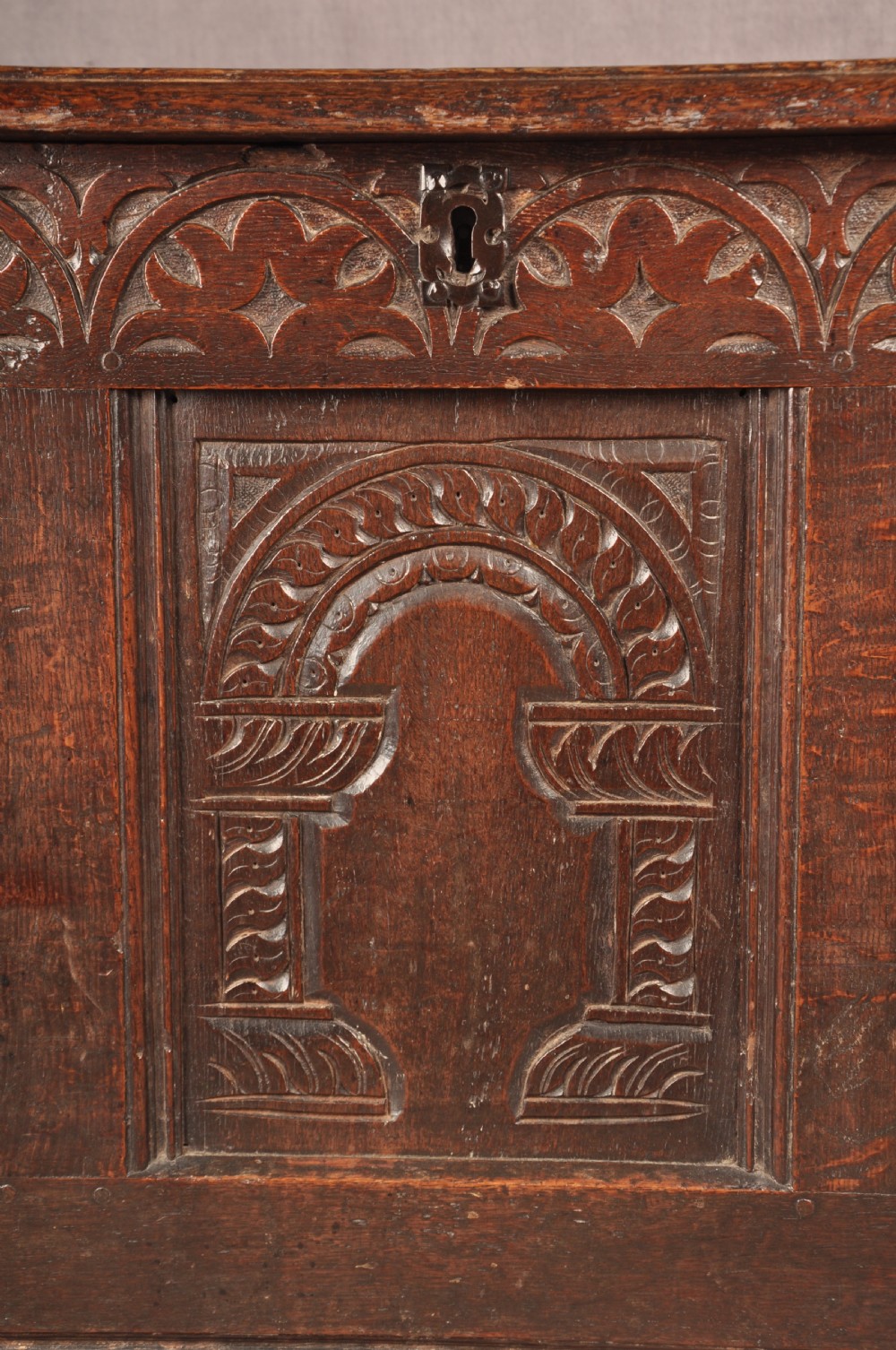A 17th-century dark oak coffer with three carved arcaded front panels, an upper carved frieze, and a central iron lock plate. View II