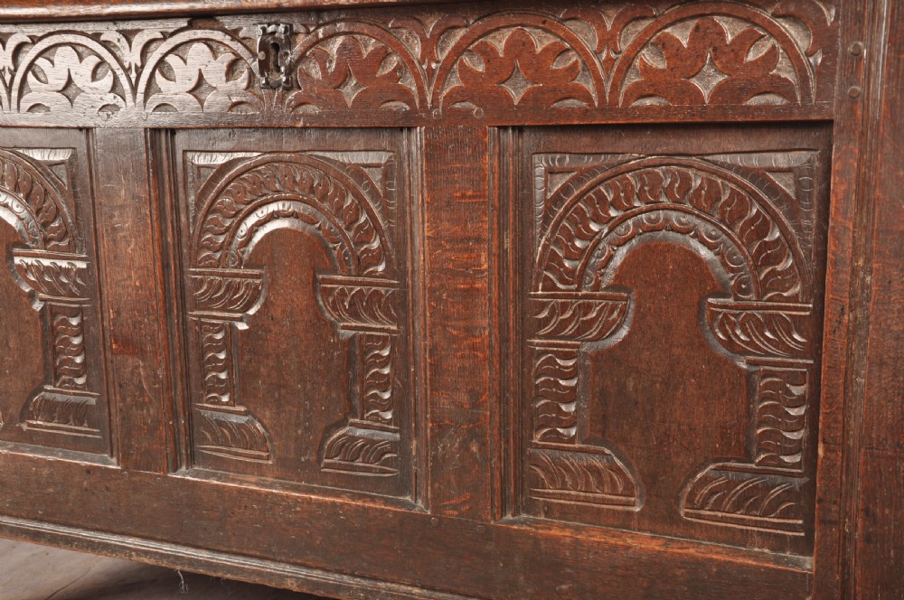 A 17th-century dark oak coffer with three carved arcaded front panels, an upper carved frieze, and a central iron lock plate. View IV