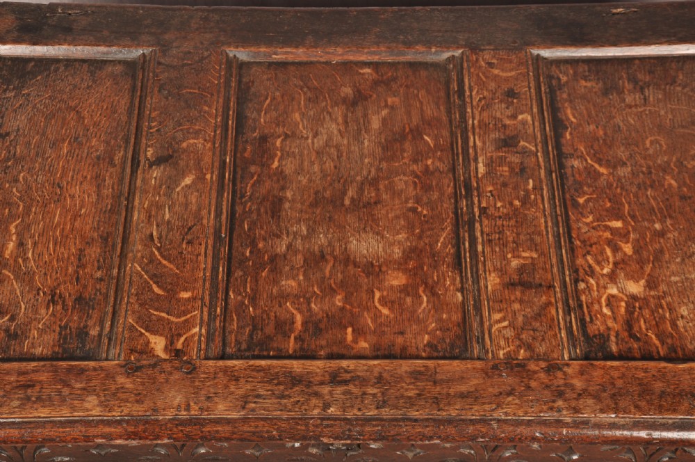 A 17th-century dark oak coffer with three carved arcaded front panels, an upper carved frieze, and a central iron lock plate. View VI