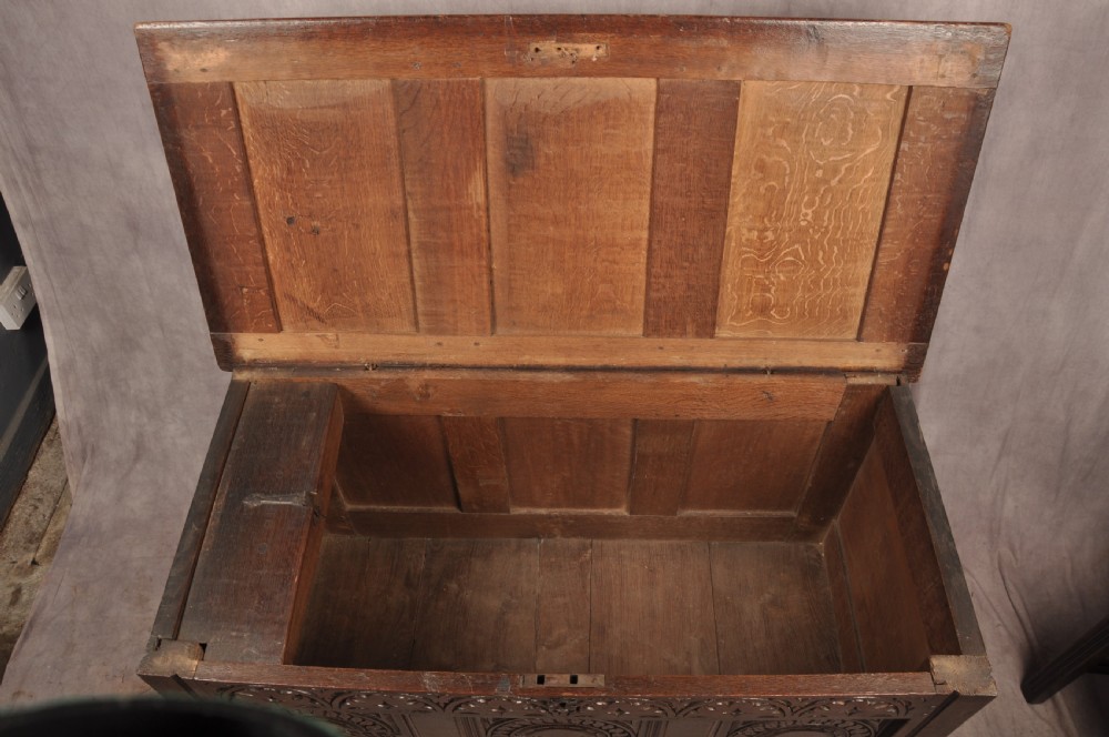 A 17th-century dark oak coffer with three carved arcaded front panels, an upper carved frieze, and a central iron lock plate. View VII