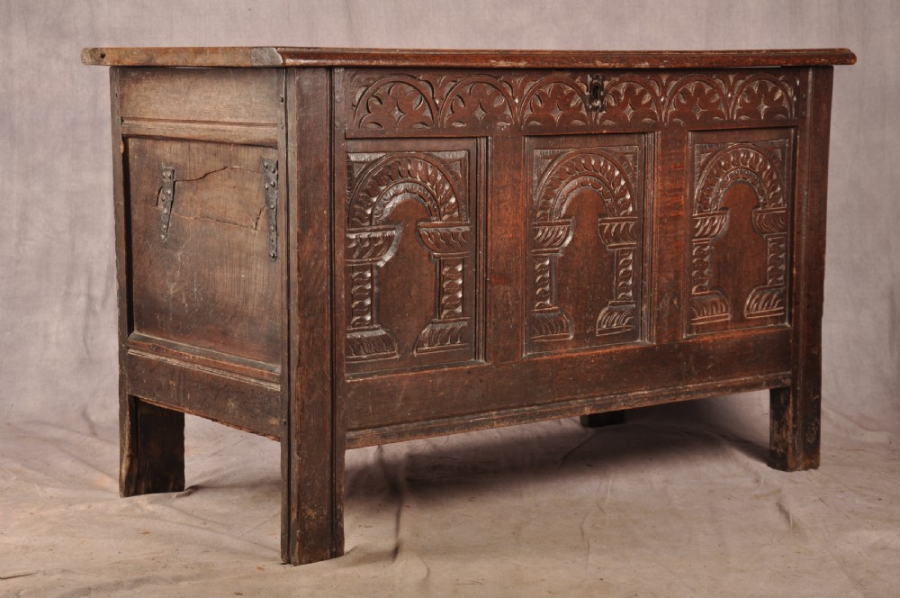 A 17th-century dark oak coffer with three carved arcaded front panels, an upper carved frieze, and a central iron lock plate. View XII