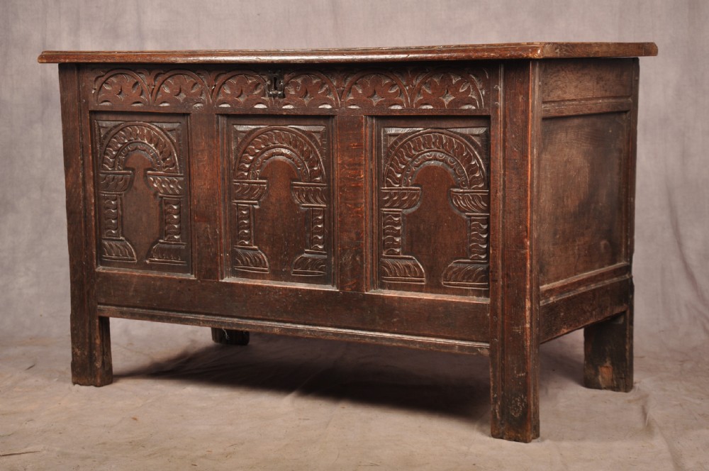 A 17th-century dark oak coffer with three carved arcaded front panels, an upper carved frieze, and a central iron lock plate. View XIII