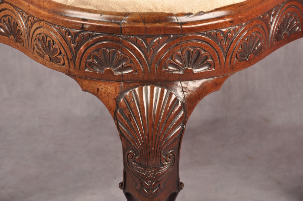 An 18th-century carved mahogany corner desk chair featuring detailed back splats, a shell-carved knee, cabriole legs, and a cream upholstered drop-in seat. View V