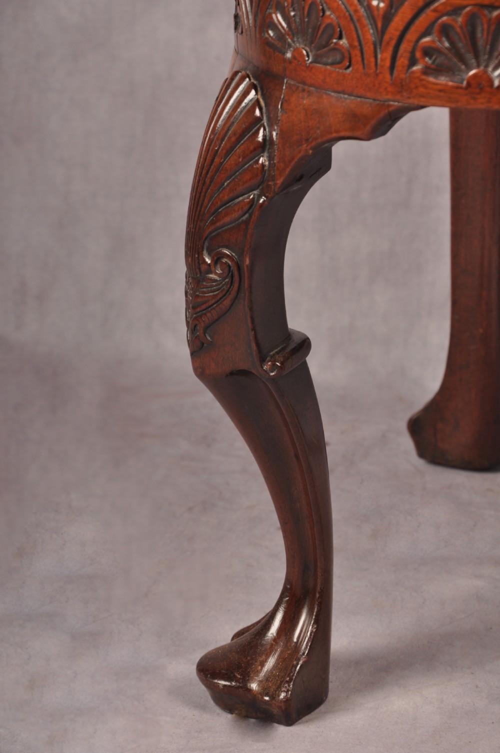 An 18th-century carved mahogany corner desk chair featuring detailed back splats, a shell-carved knee, cabriole legs, and a cream upholstered drop-in seat. View XIII