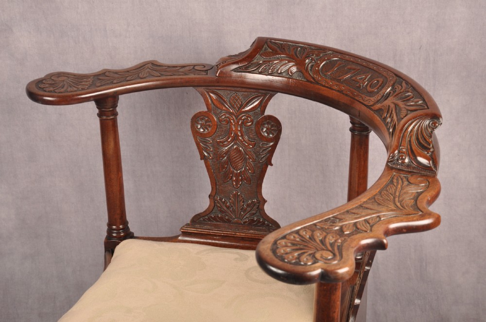 An 18th-century carved mahogany corner desk chair featuring detailed back splats, a shell-carved knee, cabriole legs, and a cream upholstered drop-in seat. View XV