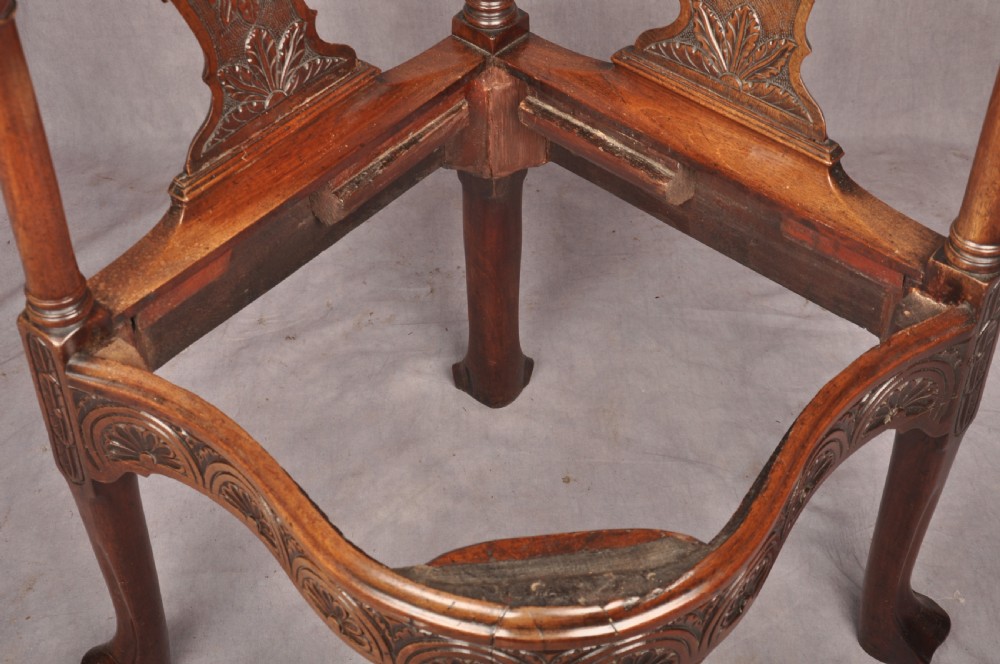 An 18th-century carved mahogany corner desk chair featuring detailed back splats, a shell-carved knee, cabriole legs, and a cream upholstered drop-in seat. View XIX