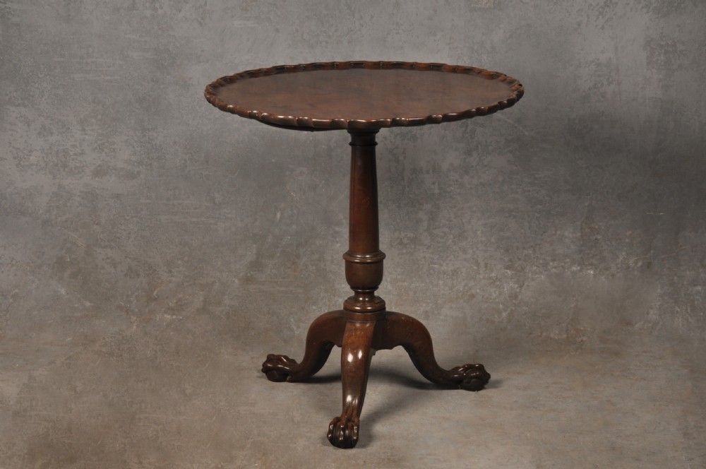 An 18th-century mahogany tripod table featuring a circular scalloped piecrust top, a turned column, and three cabriole legs ending in carved feet.
