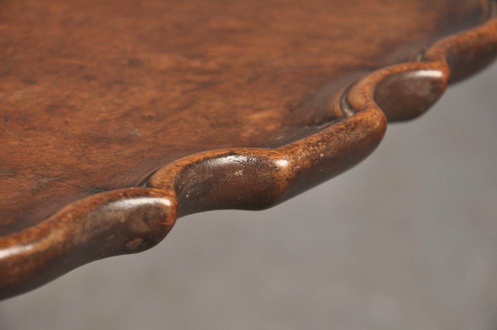 An 18th-century mahogany tripod table featuring a circular scalloped piecrust top, a turned column, and three cabriole legs ending in carved feet. View V