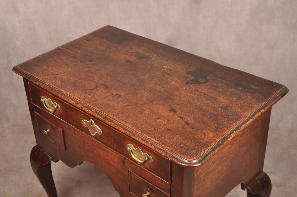 An early 18th-century dark walnut lowboy side table featuring cabriole legs with pad feet, three brass-handled drawers, and a shaped apron. View II