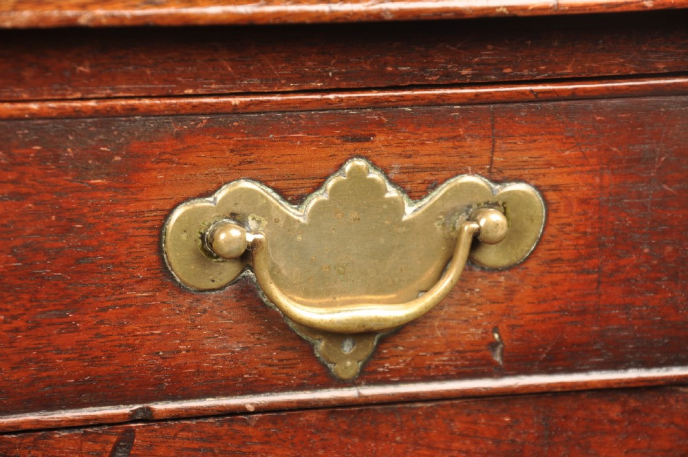 An early 18th-century dark walnut lowboy side table featuring cabriole legs with pad feet, three brass-handled drawers, and a shaped apron. View V