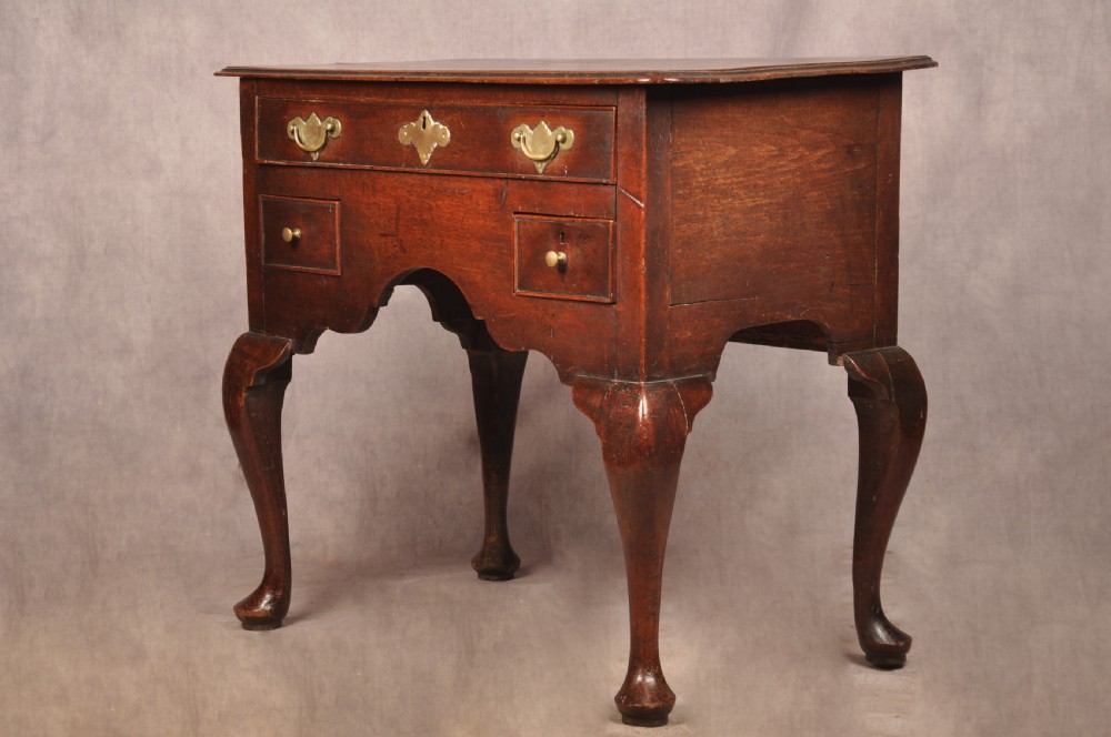An early 18th-century dark walnut lowboy side table featuring cabriole legs with pad feet, three brass-handled drawers, and a shaped apron. View XIII