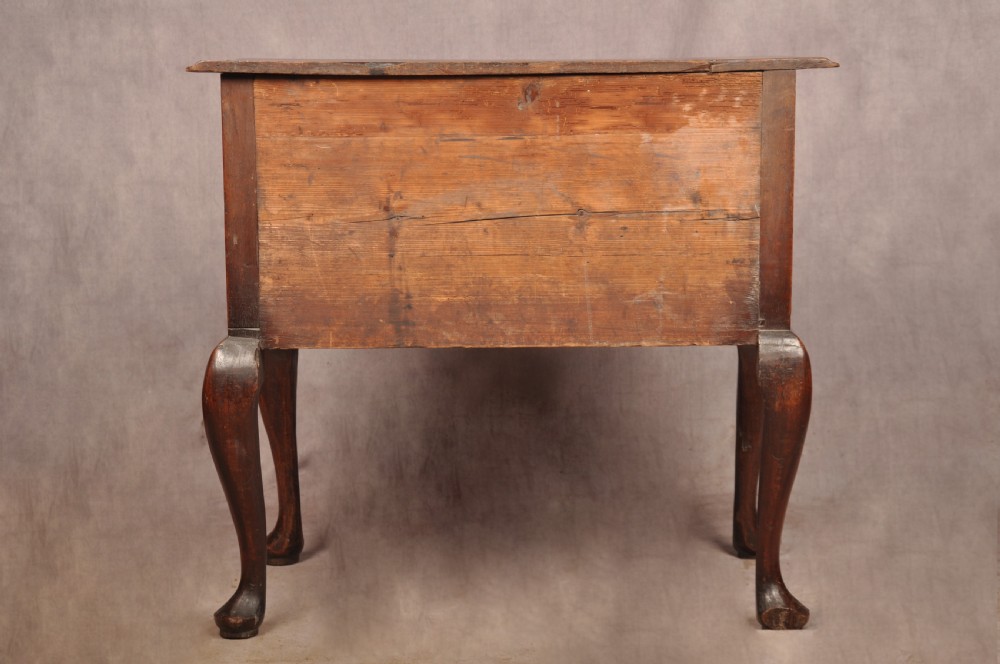 An early 18th-century dark walnut lowboy side table featuring cabriole legs with pad feet, three brass-handled drawers, and a shaped apron. View XV