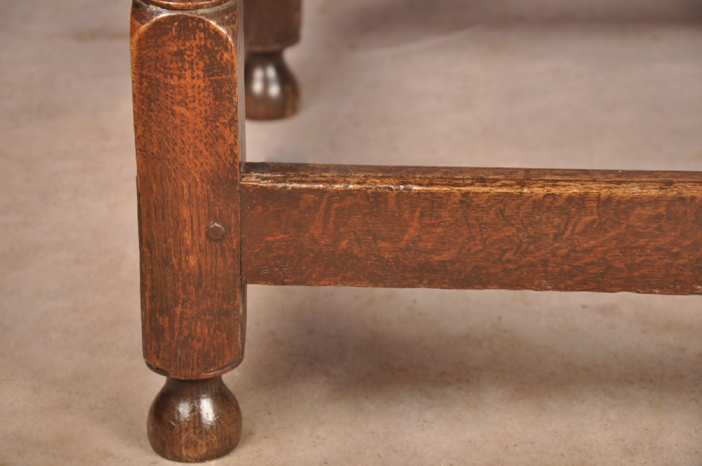 A dark oak 17th-century side table featuring four bobbin-turned legs, a lower box stretcher, and a single drawer with a teardrop brass pull. View V