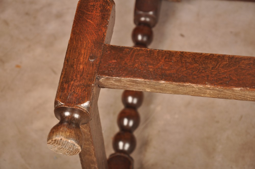 A dark oak 17th-century side table featuring four bobbin-turned legs, a lower box stretcher, and a single drawer with a teardrop brass pull. View VIII