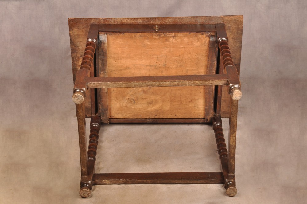 A dark oak 17th-century side table featuring four bobbin-turned legs, a lower box stretcher, and a single drawer with a teardrop brass pull. View IX