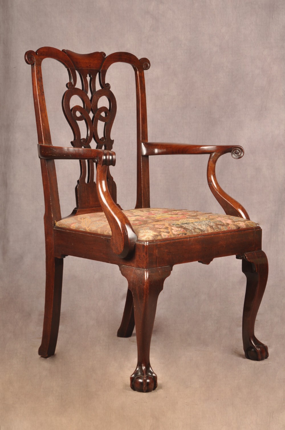 An 18th-century mahogany armchair with a carved pierced splat back, shaped arms, a tapestry-upholstered seat, and cabriole front legs ending in ball and claw feet. View XIV
