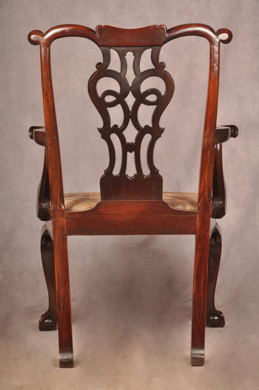 An 18th-century mahogany armchair with a carved pierced splat back, shaped arms, a tapestry-upholstered seat, and cabriole front legs ending in ball and claw feet. View XV