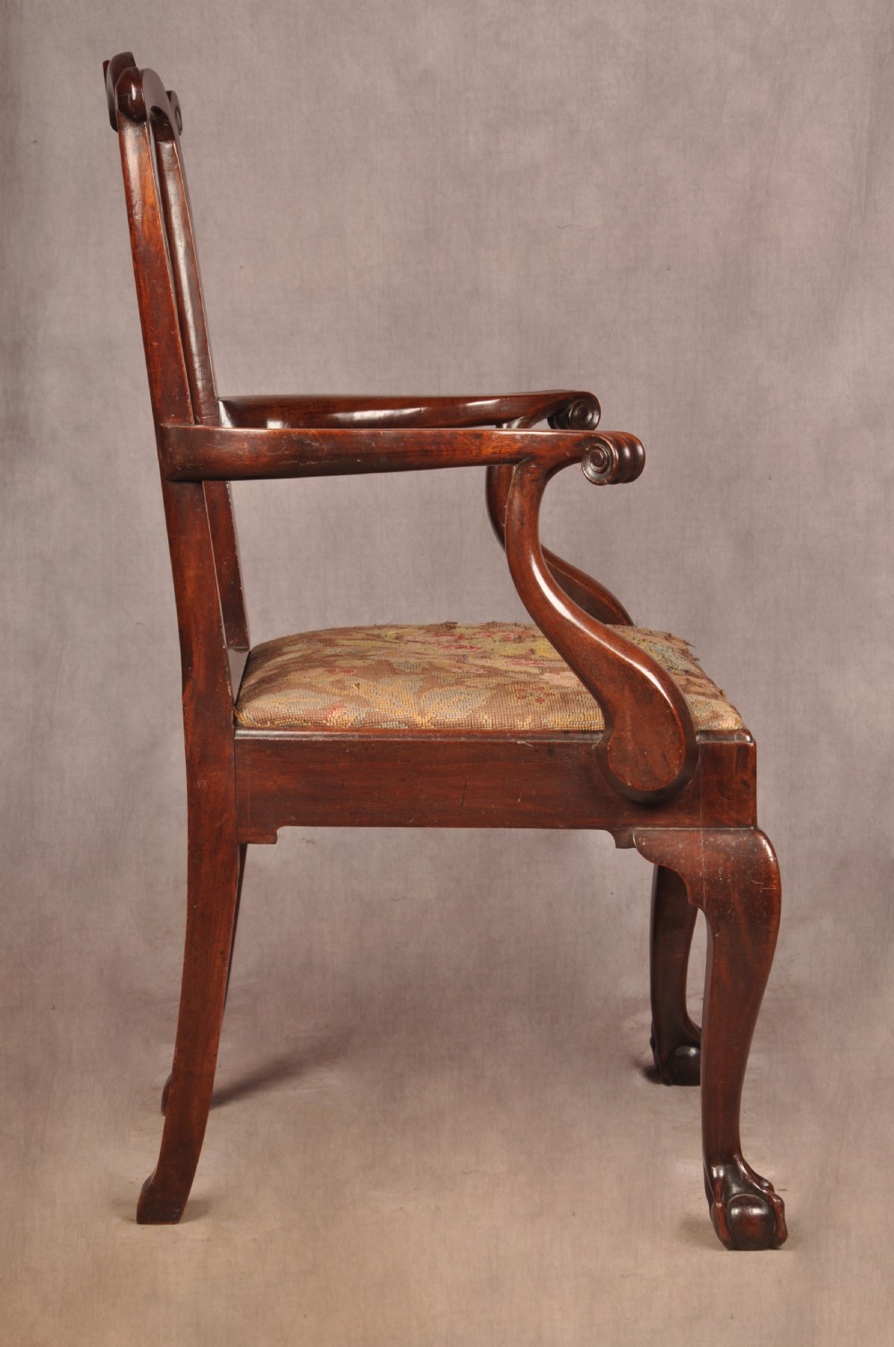 An 18th-century mahogany armchair with a carved pierced splat back, shaped arms, a tapestry-upholstered seat, and cabriole front legs ending in ball and claw feet. View XVI