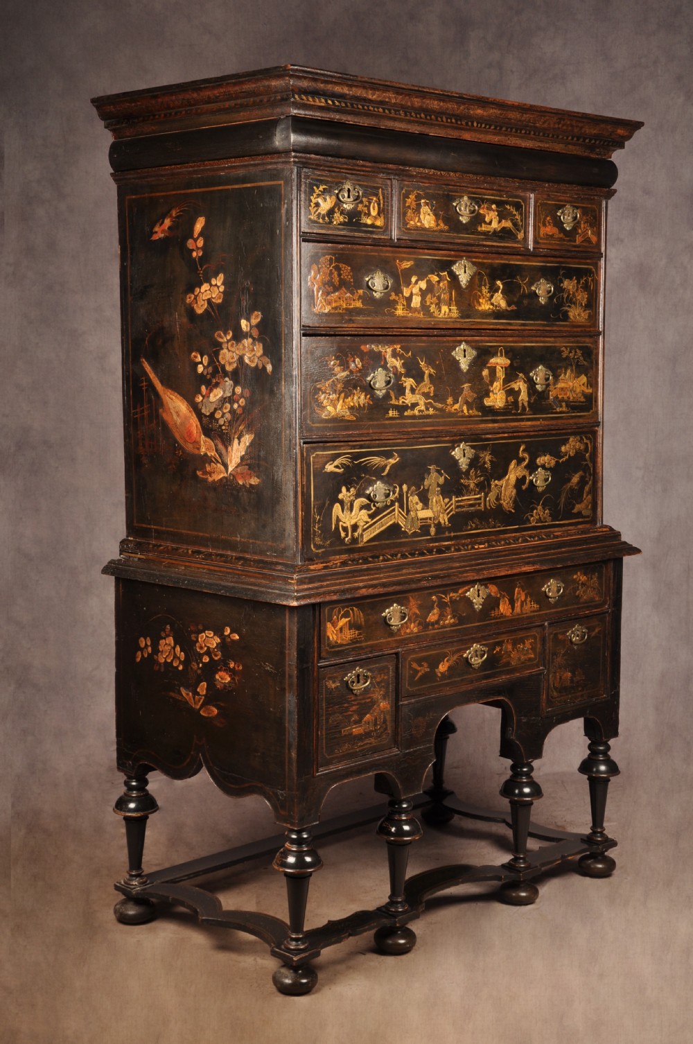 An early eighteenth-century black and gold japanned chest on stand featuring detailed Chinoiserie scenes, multiple brass drop handles, turned legs, and a shaped stretcher. View II