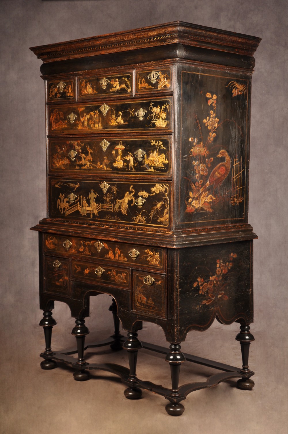 An early eighteenth-century black and gold japanned chest on stand featuring detailed Chinoiserie scenes, multiple brass drop handles, turned legs, and a shaped stretcher. View III