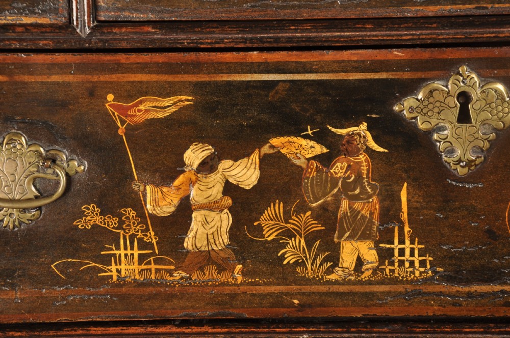 An early eighteenth-century black and gold japanned chest on stand featuring detailed Chinoiserie scenes, multiple brass drop handles, turned legs, and a shaped stretcher. View V