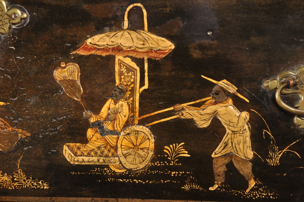 An early eighteenth-century black and gold japanned chest on stand featuring detailed Chinoiserie scenes, multiple brass drop handles, turned legs, and a shaped stretcher. View VII
