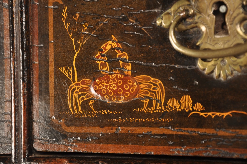 An early eighteenth-century black and gold japanned chest on stand featuring detailed Chinoiserie scenes, multiple brass drop handles, turned legs, and a shaped stretcher. View X