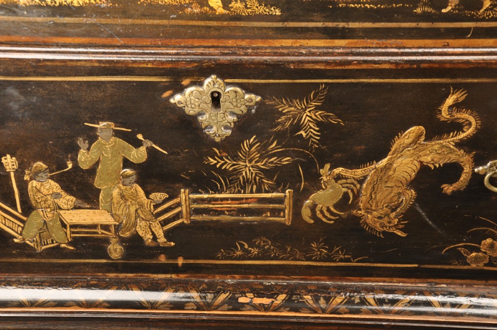 An early eighteenth-century black and gold japanned chest on stand featuring detailed Chinoiserie scenes, multiple brass drop handles, turned legs, and a shaped stretcher. View XIV