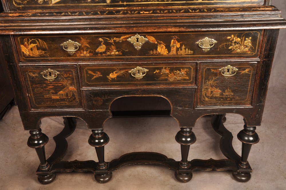 An early eighteenth-century black and gold japanned chest on stand featuring detailed Chinoiserie scenes, multiple brass drop handles, turned legs, and a shaped stretcher. View XV