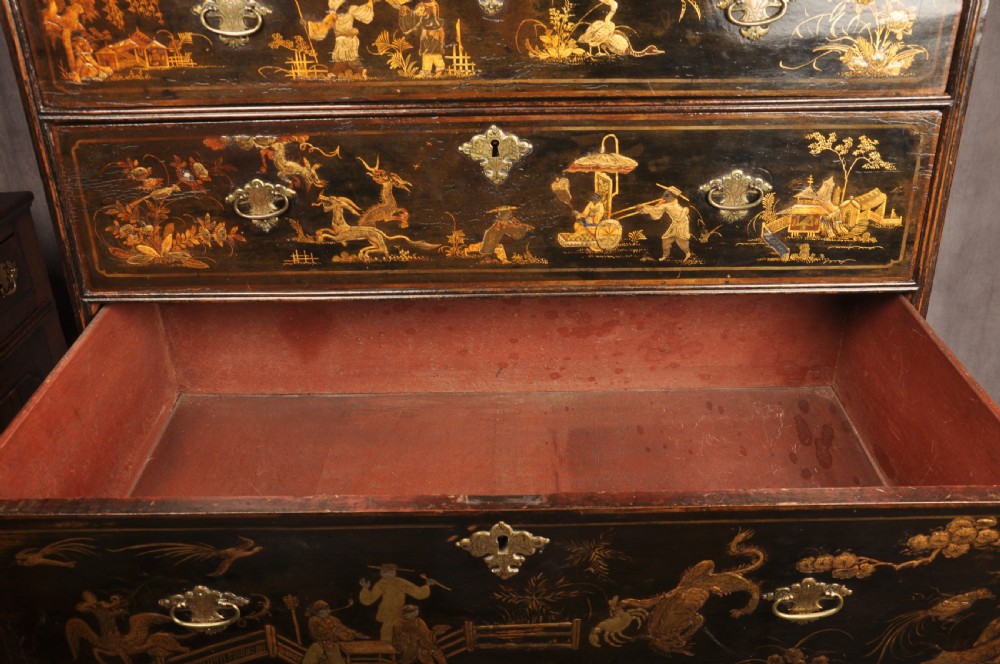 An early eighteenth-century black and gold japanned chest on stand featuring detailed Chinoiserie scenes, multiple brass drop handles, turned legs, and a shaped stretcher. View XVI