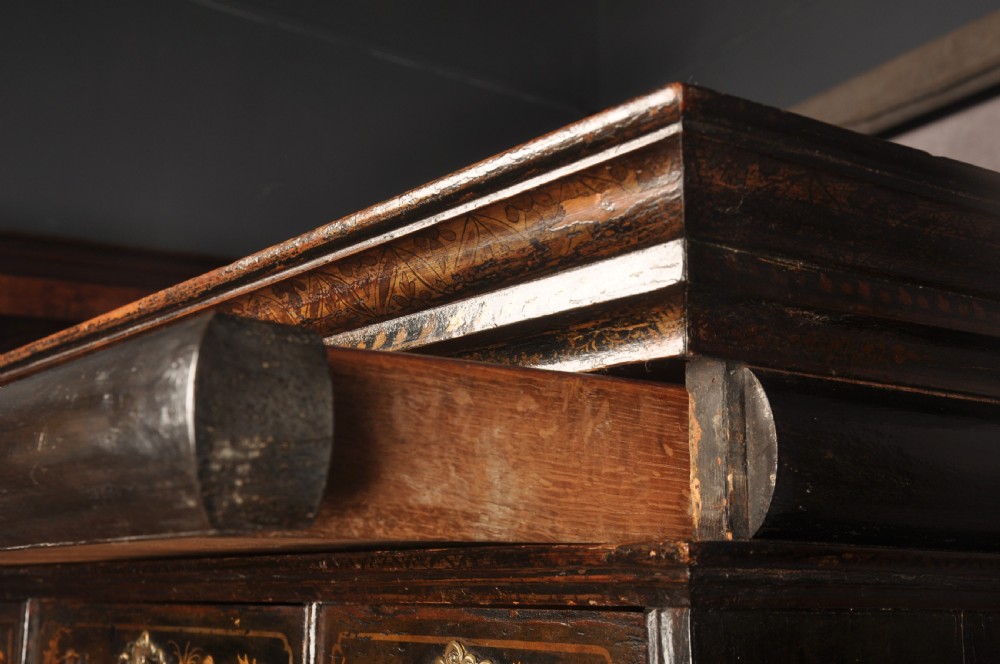 An early eighteenth-century black and gold japanned chest on stand featuring detailed Chinoiserie scenes, multiple brass drop handles, turned legs, and a shaped stretcher. View XXI