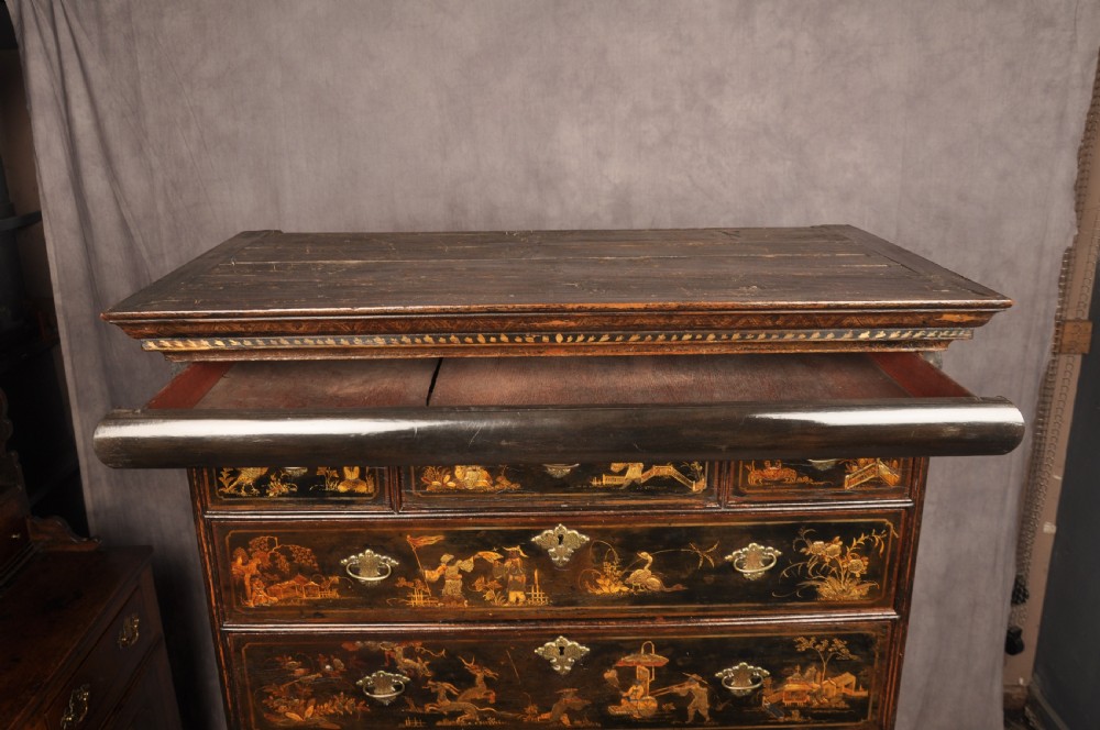 An early eighteenth-century black and gold japanned chest on stand featuring detailed Chinoiserie scenes, multiple brass drop handles, turned legs, and a shaped stretcher. View XXII