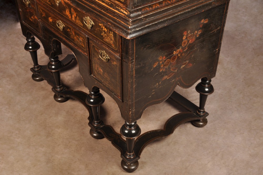 An early eighteenth-century black and gold japanned chest on stand featuring detailed Chinoiserie scenes, multiple brass drop handles, turned legs, and a shaped stretcher. View XXIV