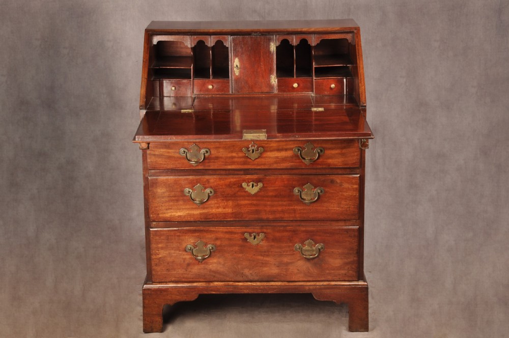 An early 18th-century mahogany slope-front bureau with three graduated drawers, brass handles, keyhole escutcheons, and bracket feet. View III