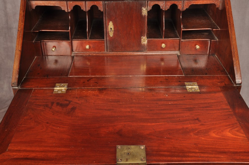 An early 18th-century mahogany slope-front bureau with three graduated drawers, brass handles, keyhole escutcheons, and bracket feet. View IV