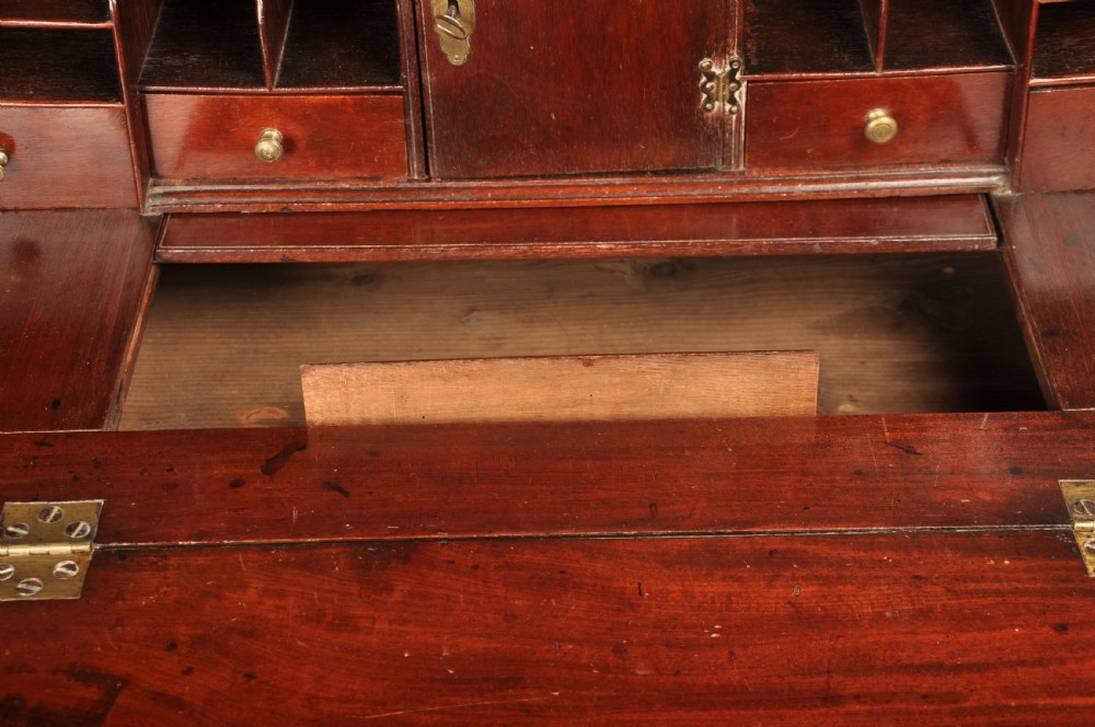 An early 18th-century mahogany slope-front bureau with three graduated drawers, brass handles, keyhole escutcheons, and bracket feet. View V