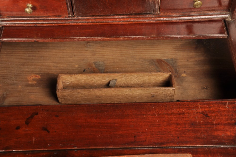 An early 18th-century mahogany slope-front bureau with three graduated drawers, brass handles, keyhole escutcheons, and bracket feet. View VII