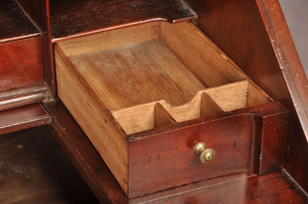 An early 18th-century mahogany slope-front bureau with three graduated drawers, brass handles, keyhole escutcheons, and bracket feet. View IX
